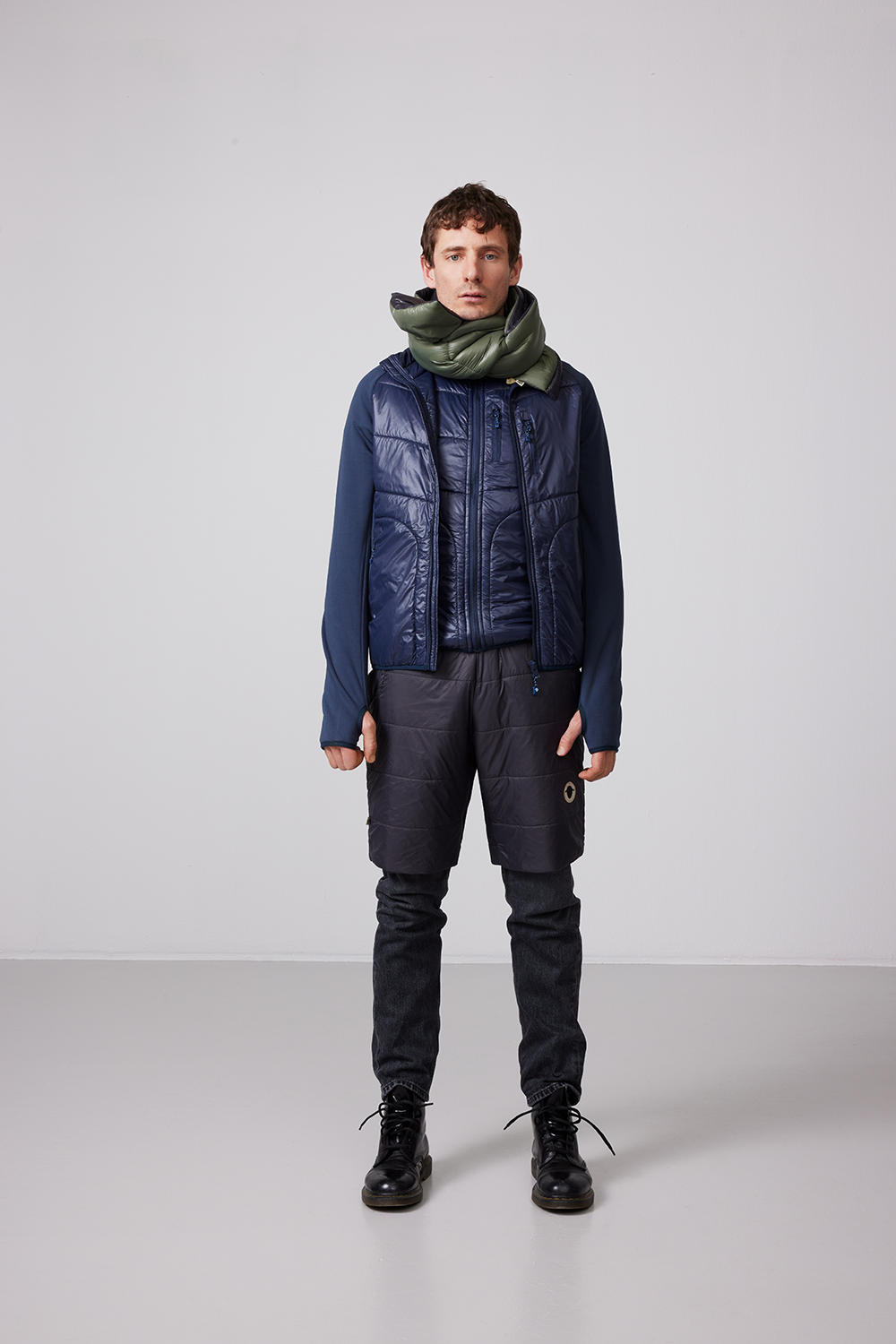 En man står iklädd en SUFFOLK Hybrid jacka från Wool Rebel, fodrad med FÅRTEX. Jackan har en mörkblå färg.